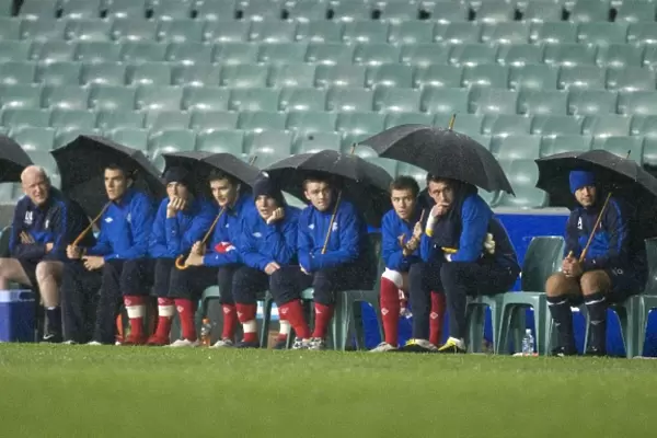Rangers FC Braves the Storm: Players and Coaching Staff Huddle Under Umbrellas at Sydney Festival of Football 2010