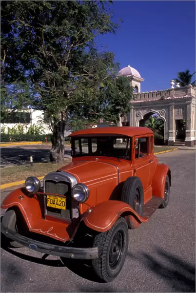 Cuba, Cien Fuergos, Old Model A Ford and colorful architecture behind