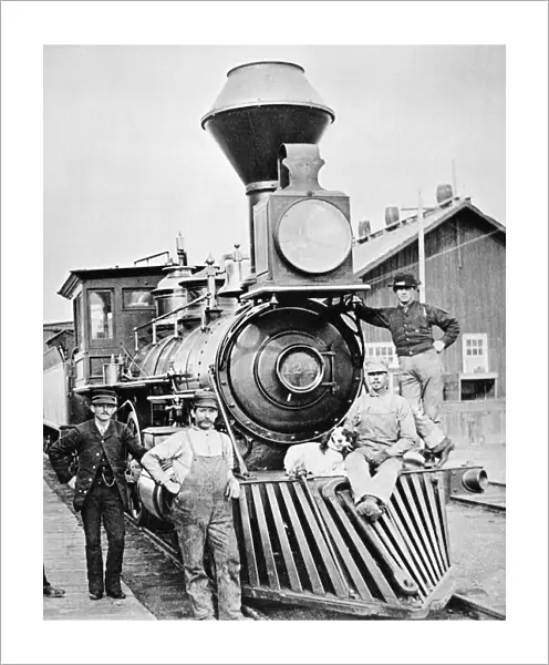 LOCOMOTIVE, 1883. The conductor, crew and canine mascot of a Central Pacific Railroad train posing by the locomotive during a station stop at Mill City, Nevada. Photographed in 1883