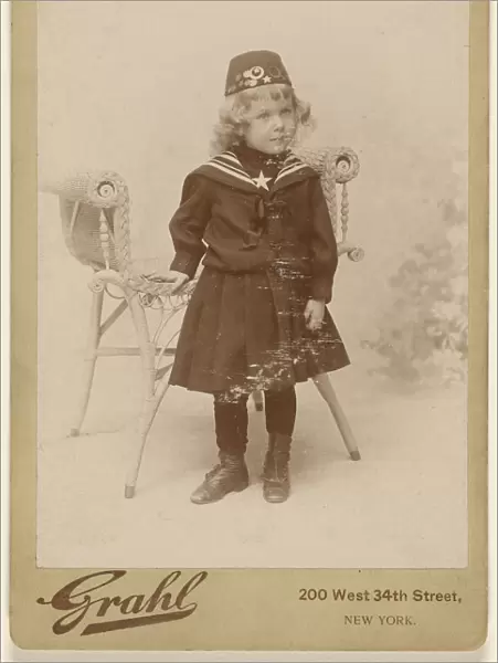 Little girl standing chair wearing fez Grahl