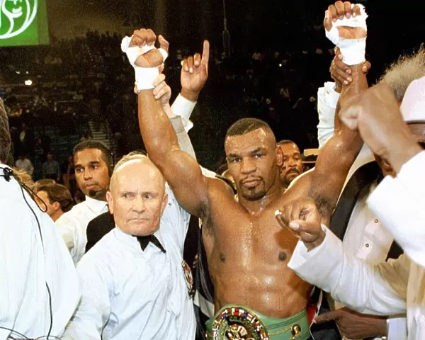 Mike Tyson has his arms raised by referee Mills Lane after beating Frank Bruno for