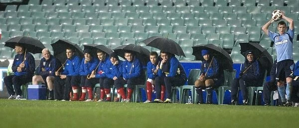 Rangers FC Braves the Storm: Players and Coaching Staff Huddle Under Umbrellas at Sydney Festival of Football 2010