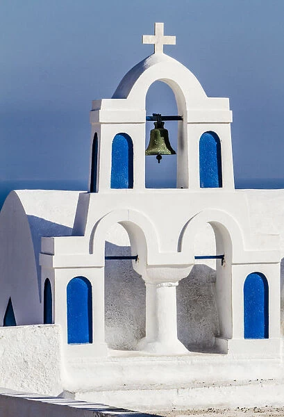 Oia, Greece. Greek Orthdox Church steeple, cross, bell, and blue arches against Aegean