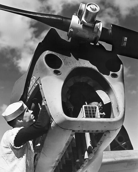 An Aviation Machinists Mate of the U. S. Navy works on the powerhouse of a Curtiss SO3C Seamew floatplane scout, mid-20th century