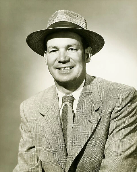 Businessman wearing fedora hat, smiling, (B&W), portrait