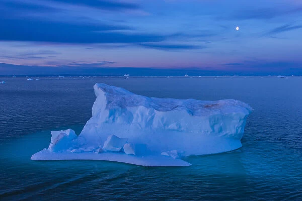 A large iceberg floats in Scorsby Sound at twilight