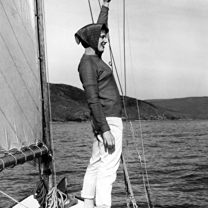 Girl in headscarf at the front of a sailing boat waving
