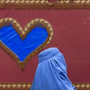 An Afghan woman walks past a decoration on the side of a traditional Reksha motor-taxi