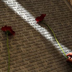 A man lays a flower on a monument engraved with names of victims of the September 11th