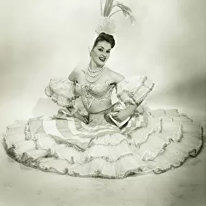 Woman in Latino dance costume sitting in studio, holding drum, (B&W)